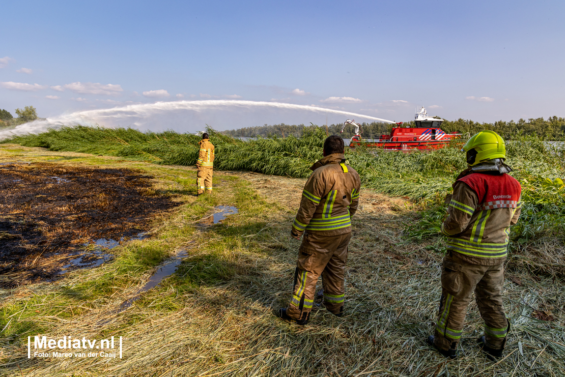 Brandweer blust brandend riet in Rhoon